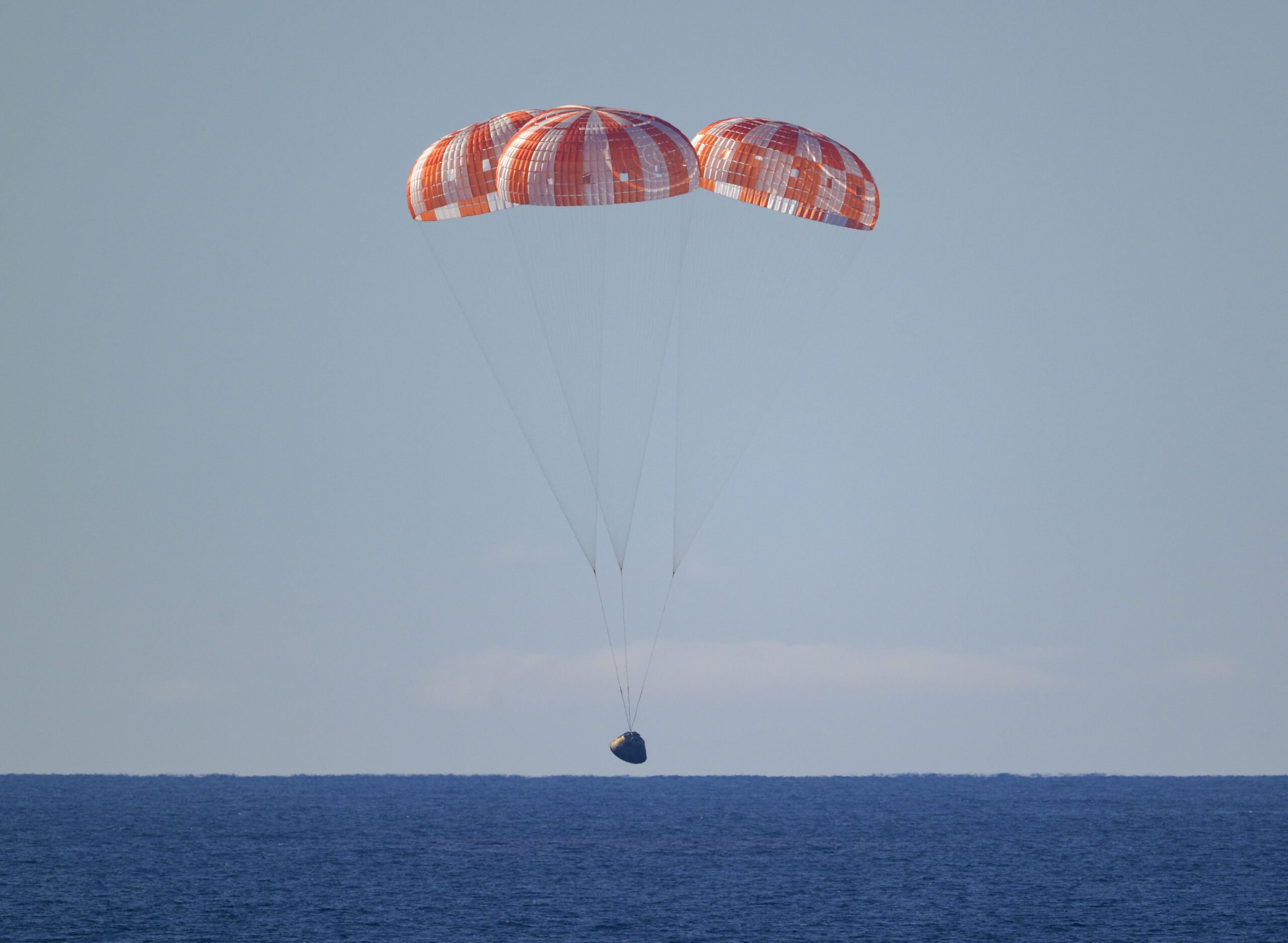 La capsule Orion stabilisée par ses trois parachutes au-dessus de l'océan Pacifique.