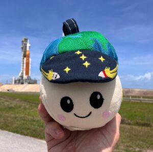 Rise, l'indicateur d'apesanteur de la mission Artemis II, devant la fusée SLS de la mission Artemis II.